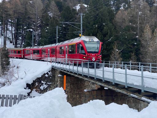 A red train on its way on a snowy day in Morteratsch, Switzerland