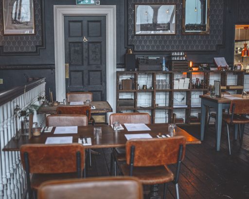 A vintage style restaurant interior with dark wooden tables and leather chairs