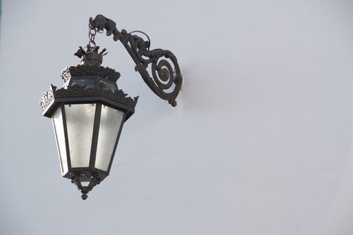 A closeup shot of an old-fashioned metal lamp hanging on a white wall