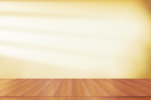 A empty wooden table in front of dim light and shadow on a wall from the window