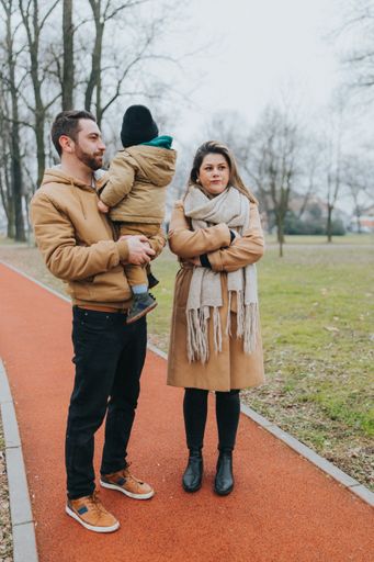 A vertical shot of a young family walking in the park on a freezing cold day