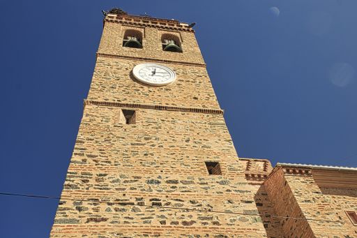 A low angle shot of an old brick clock tower and clear blue sky - perfect for background