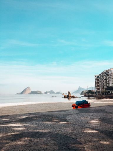 A vertical shot of a white sandy beach in Rio de Janeiro, Brazil at daytime with a blue sky in the background