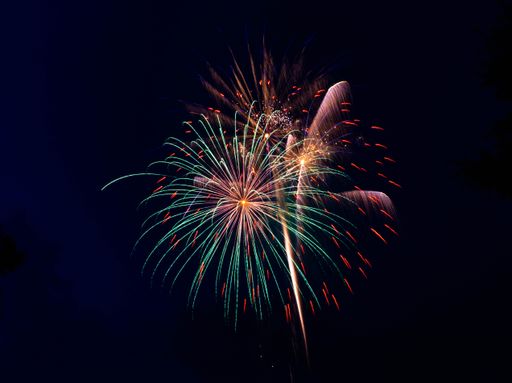 The bright colorful splashes of firework in the dark sky during a national holiday