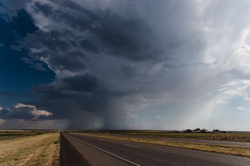 The long asphalt road under the cloudy rainy sky