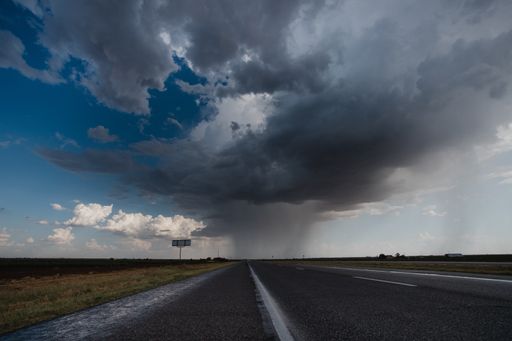 The long asphalt road under the cloudy rainy sky