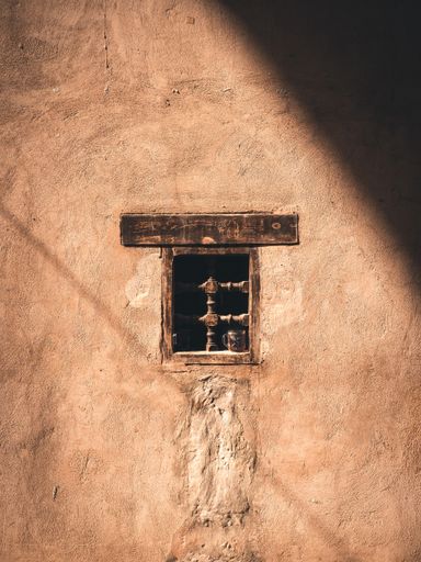 A beautiful shot of a small old widow on a stone old wall with sunlight and shadow in Aswan, Egypt