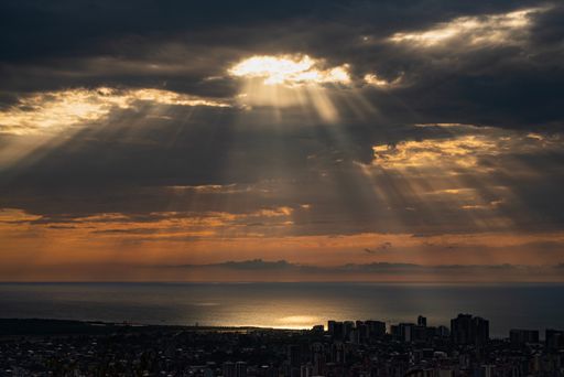 A scenic view of sun rays passing through dark clouds over a coastal town