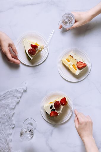 A top view shot of three plates with strawberry cake pieces and a glass