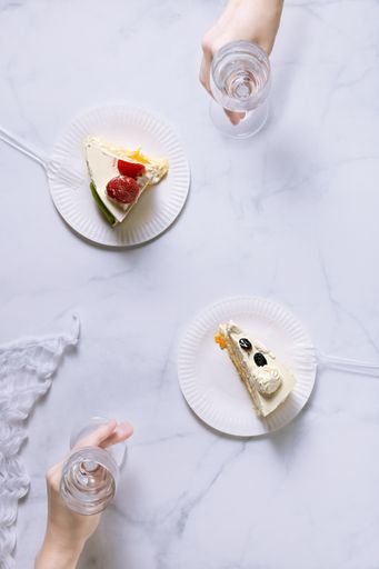 A top view shot of two plates with berry cakes and cheering glasses