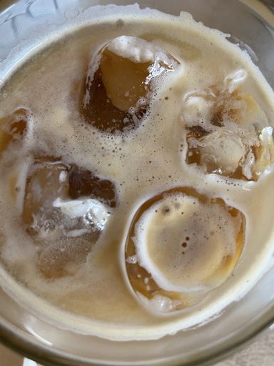 A vertical closeup shot of a cup of iced coffee with ice cubes