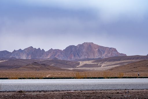 A road passing through a deserted area with rocky mountains in the background
