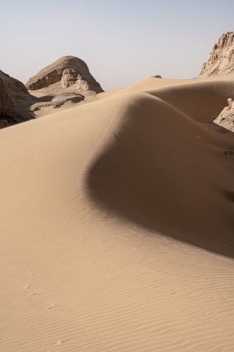 A vertical shot of a sand desert under the bright sunlight