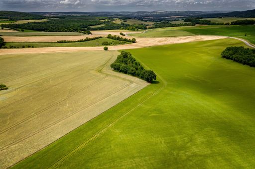 An aerial shot of a grassland under during a cloudy weather