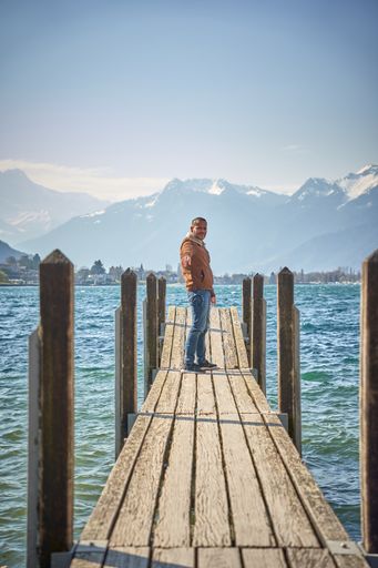 A vertical shot of a young male standing on the jetty in Montreux, Switzerland