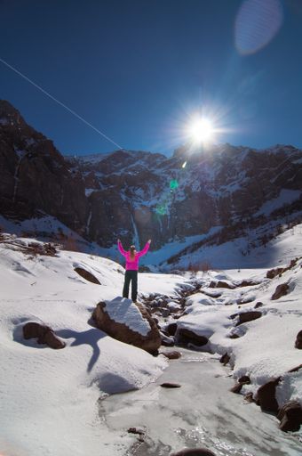 A girl in Winterwanderland (Adelboden), Bern, Switzerland in front of frozen waterfall