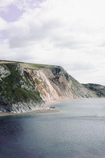 A beautiful shot of a mountain overlooking the durdle door beach under a cloudy blue sky