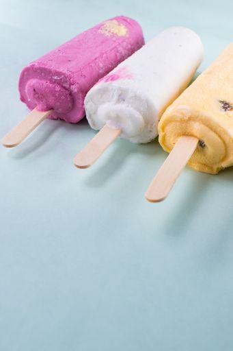 A vertical closeup shot of different flavored ice creams on a blue background