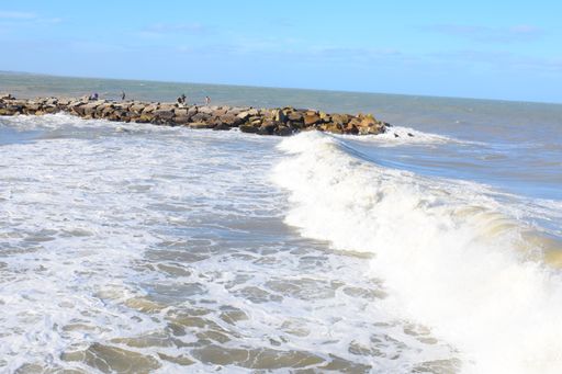 A beautiful shot of a wavy sea crashing a sandy beach under a blue sky on a sunny day