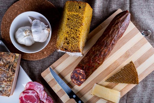 A closeup shot of a piece of parmesan cheese Ventricina sausage and bread on a cutting board
