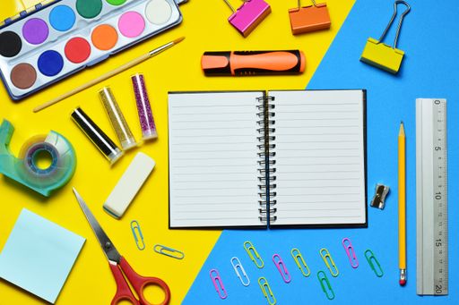 A closeup of various school supplies against the blue and yellow background. Top view.