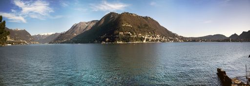 A panoramic shot of a sea surrounded by mountains with a clear blue sky in the background