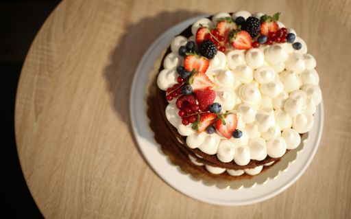 A top view of fresh tasty cake with berries and fruits on a wooden table