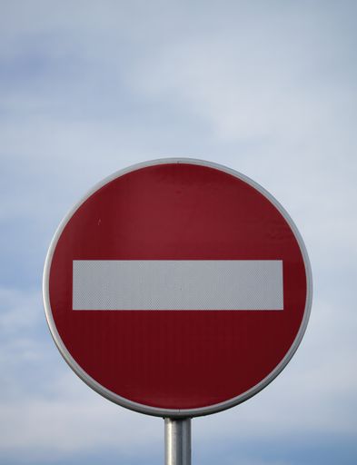 A vertical shot of a no entry sign against a cloudy blue sky