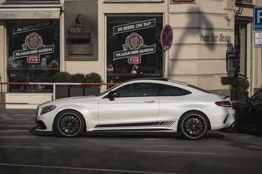 A modern white fast car parked in the street. Mercedes Benz C63 AMG