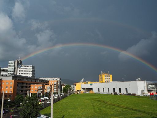 beautiful rainbow over the Siemens building in the city of Linz, Austria. Rainy weather with dramatic clouds and rainbow in the city