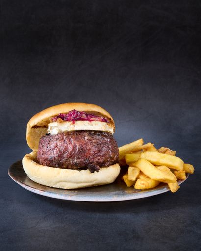 a vertical shot of The Blarney Burger with and french fries on side in a plate.