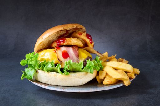 A studio shot of a fresh burger with fries on dark background
