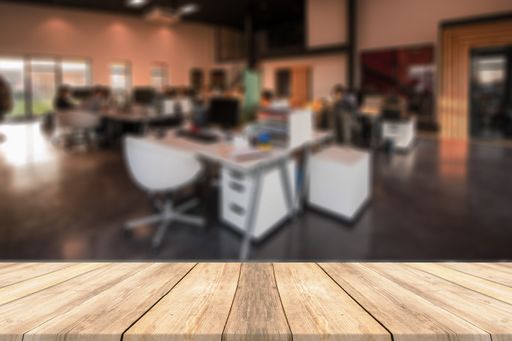 A shallow focus shot of a modern office setting with a wooden surface on the foreground