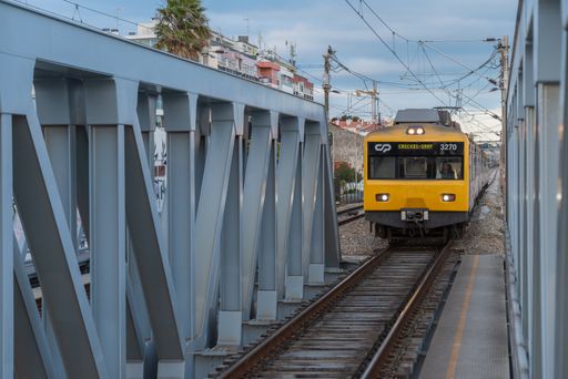 A yellow urban train of the CP company circulating on the railway bridge
