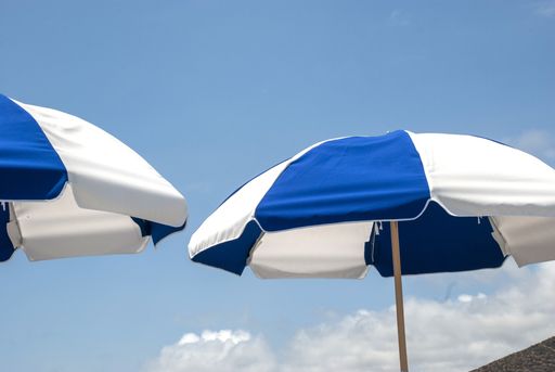 A close up shot of blue and white park umbrellas under the sky