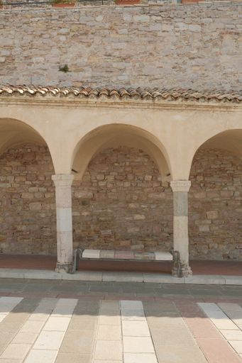 A vertical shot of the empty bench between arches. Assisi. Italy.