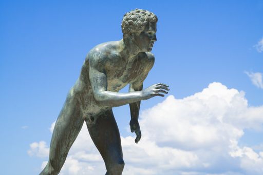 A runner sculpture in Achilleion, Corfu, Greece against the cloudy sky