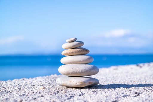 A closeup shot of pebbles stacked on each other in a balance with the blue sea in the background