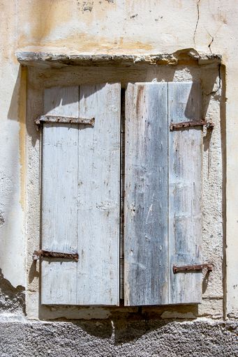 A vertical shot of a small old wooden greek door