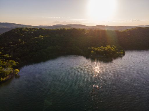 A high angle shot of a shining lake against foliage hills