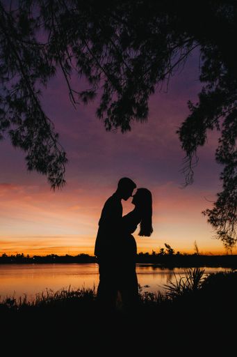 A vertical picture of beautiful silhouettes of lovers against a mesmerizing sky