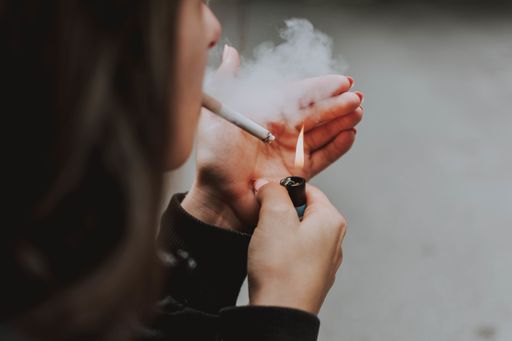 A selective closeup shot of a female lighting up a cigarette with a lighter