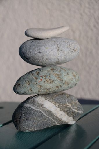 A vertical shot of stacked stones on a wooden table with a blurry background - concept of zen energy