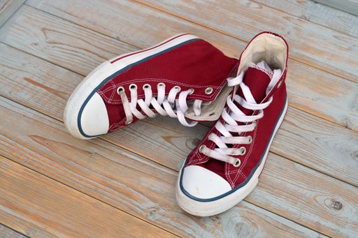 A high angle view of red high top sneakers on a wooden floor under the lights