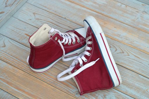 A high angle view of red high top sneakers on a wooden floor under the lights