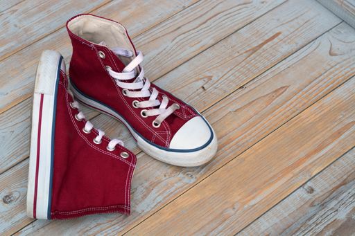 A high angle view of red high top sneakers on a wooden floor under the lights