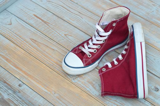 A high angle view of red high top sneakers on a wooden floor under the lights