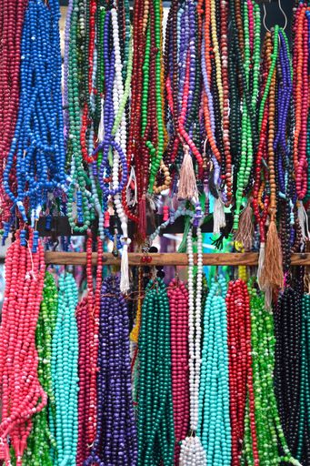 A vertical shot of colorful bead necklaces hanging at a market under the sunlight
