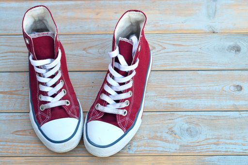 A high angle view of red high top sneakers on a wooden floor under the lights