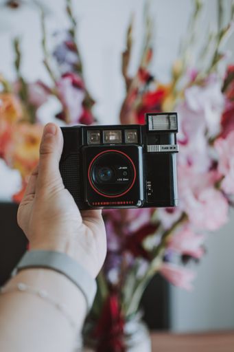 A vertical selective shot of a person holding black photo camera